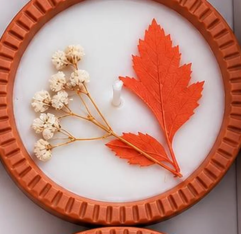 A red leaf and a posy of cream buds pressed into the wax.